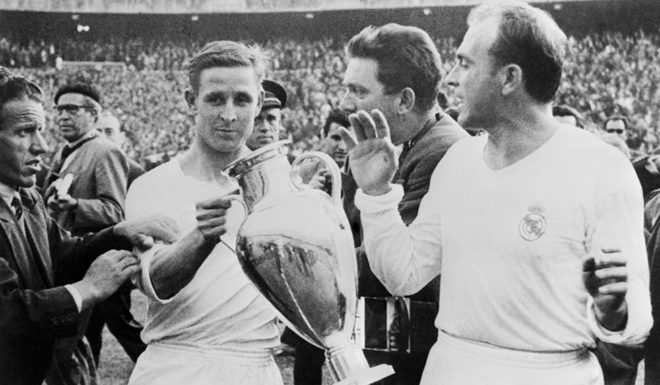 l'attaquant français du Real Madrid, Raymond Kopa, accompagné de l'attaquant Alfredo Di Stefano, tient la Coupe d'Europe dans ses mains, le 30 mai 1957 au stade Santiago Bernabeu à Madrid, après la victoire du Real Madrid (2-0) sur la Fiorentina (Ita), en finale de la Coupe d'Europe de football. Real Madrid's French forward Raymond Kopa holds the European Cup as teammate Alfredo Di Stefano looks on 30 May 1957 at Santiago Bernabeu stadium in Madrid, after Real Madrid's victory (2-0) over Fiorentina (Ita) in the Soccer European Cup final. AFP PHOTO (Photo credit should read STAFF/AFP/Getty Images)