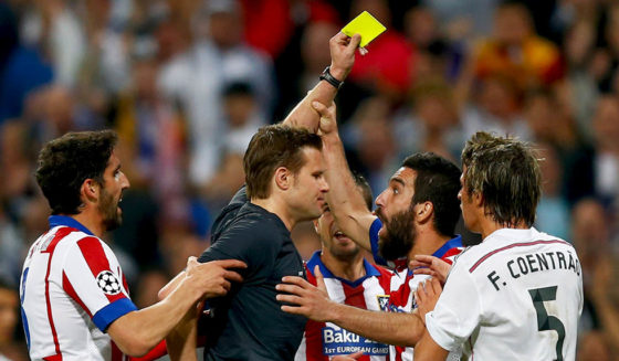 MADRID, SPAIN - APRIL 22: Arda Turan of Atletico Madrid (2R) grabs the arm of referee Felix Brych as he is shown a second yellow card and is sent off during the UEFA Champions League quarter-final second leg match between Real Madrid CF and Club Atletico de Madrid at Bernabeu on April 22, 2015 in Madrid, Spain. (Photo by Clive Rose/Getty Images)