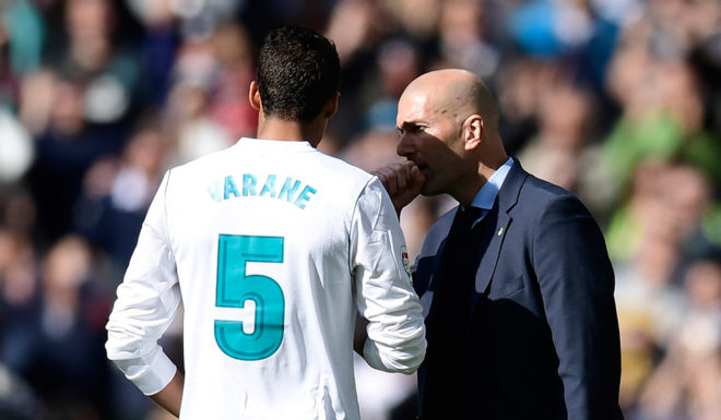 Real Madrid's French coach Zinedine Zidane (R) talks with Real Madrid's French defender Raphael Varane during the Spanish league football match between Real Madrid CF and Club Atletico de Madrid at the Santiago Bernabeu stadium in Madrid on April 8, 2018. / AFP PHOTO / JAVIER SORIANO (Photo credit should read JAVIER SORIANO/AFP/Getty Images)