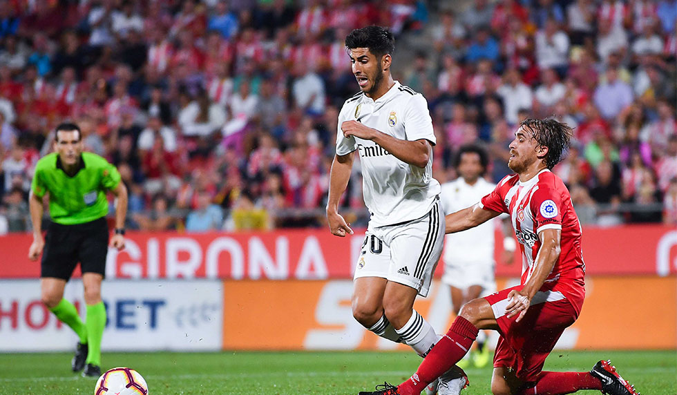 GIRONA, SPAIN - AUGUST 26: Marco Asensio of Real Madrid CF is brought down by Marc Muniesa of Girona FC during the La Liga match between Girona FC and Real Madrid CF at Montilivi Stadium on August 26, 2018 in Girona, Spain. (Photo by David Ramos/Getty Images)
