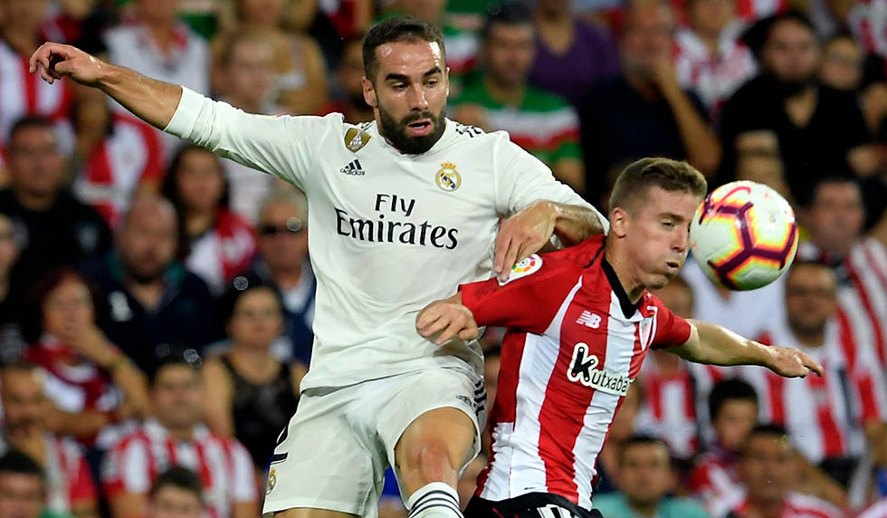 Real Madrid's Spanish defender Dani Carvajal (L) vies wuth Athletic Bilbao's Spanish forward Iker Muniain during the Spanish league football match between Athletic Club Bilbao and Real Madrid CF at the San Mames stadium in Bilbao on September 15, 2018. (Photo by LLUIS GENE / AFP) (Photo credit should read LLUIS GENE/AFP/Getty Images)