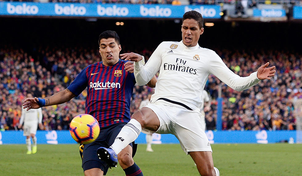 Barcelona's Uruguayan forward Luis Suarez (L) vies with Real Madrid's French defender Raphael Varane during the Spanish league football match between FC Barcelona and Real Madrid CF at the Camp Nou stadium in Barcelona on October 28, 2018. (Photo by Josep LAGO / AFP) (Photo credit should read JOSEP LAGO/AFP/Getty Images)