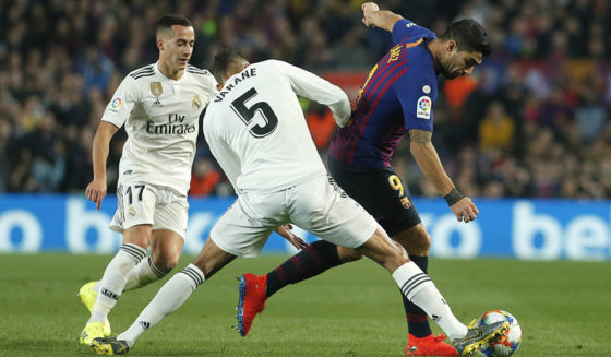 (FromL) Real Madrid's Spanish midfielder Lucas Vazquez and Real Madrid's French defender Raphael Varane vie for the ball with Barcelona's Uruguayan forward Luis Suarez during the Spanish Copa del Rey (King's Cup) semi-final first leg football match between FC Barcelona and Real Madrid CF at the Camp Nou stadium in Barcelona on February 6, 2019. (Photo by PAU BARRENA / AFP) (Photo credit should read PAU BARRENA/AFP/Getty Images)