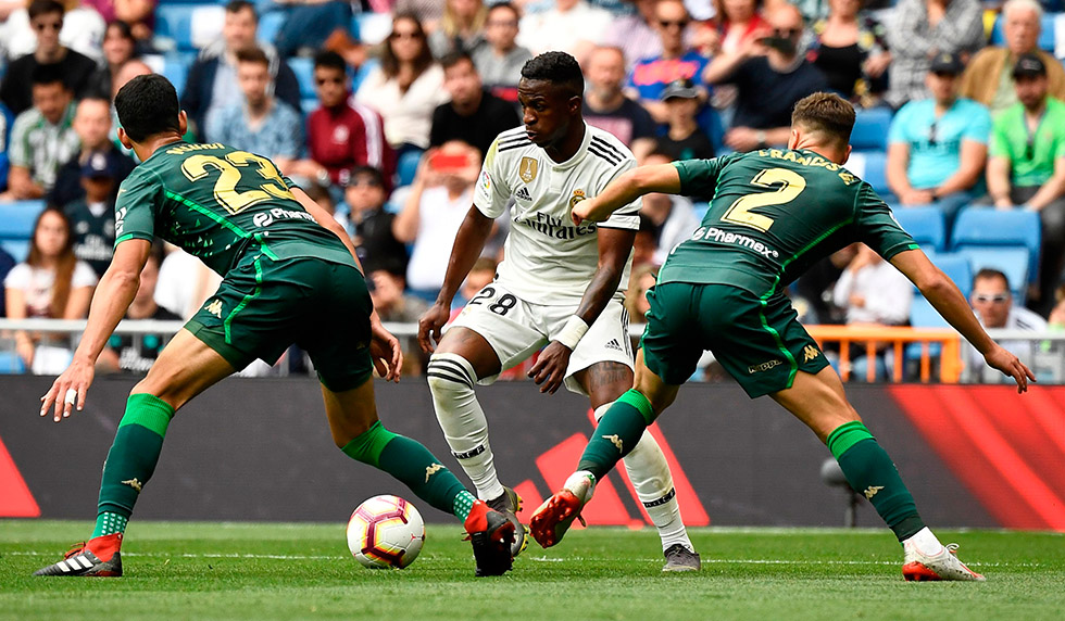 Real Madrid's Brazilian forward Vinicius Junior (C) challenges Real Betis' Algerian defender Aissa Mandi (L) and Real Betis' Spanish defender Francis during the Spanish League football match between Real Madrid and Real Betis at the Santiago Bernabeu stadium in Madrid on May 19, 2019. (Photo by PIERRE-PHILIPPE MARCOU / AFP) (Photo credit should read PIERRE-PHILIPPE MARCOU/AFP/Getty Images)