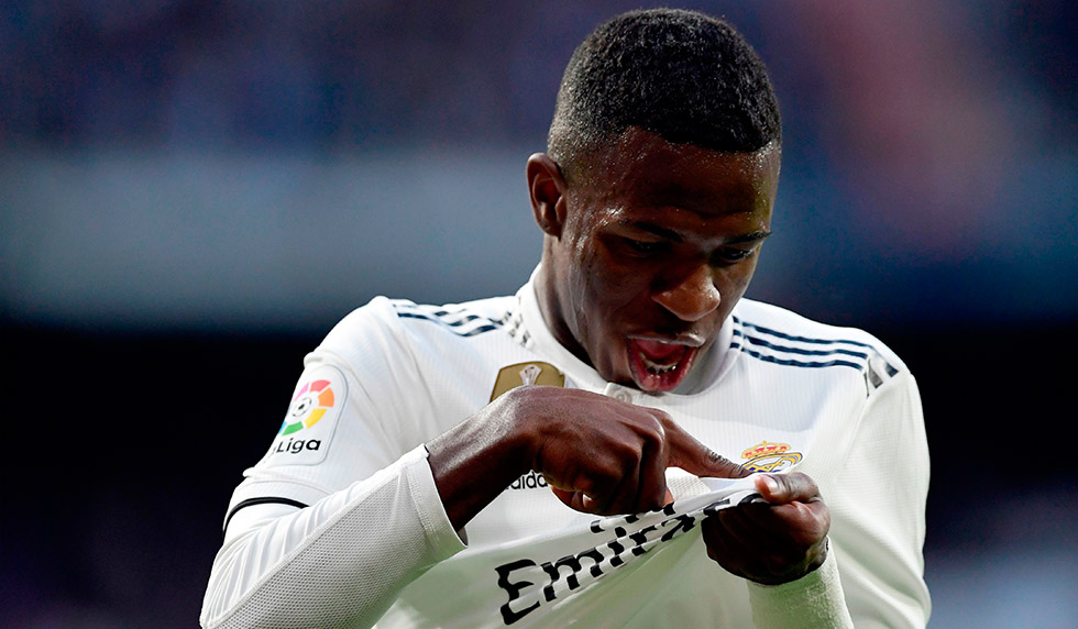 Real Madrid's Brazilian forward Vinicius Junior points at his jersey's badge to celebrate Valladolid's own goal during the Spanish league football match between Real Madrid CF and Real Valladolid FC at the Santiago Bernabeu stadium in Madrid on November 3, 2018. (Photo by JAVIER SORIANO / AFP) / The erroneous mention[s] appearing in the metadata of this photo by JAVIER SORIANO has been modified in AFP systems in the following manner: [to celebrate Valladolid's own goal] instead of [after scoring a goal]. Please immediately remove the erroneous mention[s] from all your online services and delete it (them) from your servers. If you have been authorized by AFP to distribute it (them) to third parties, please ensure that the same actions are carried out by them. Failure to promptly comply with these instructions will entail liability on your part for any continued or post notification usage. Therefore we thank you very much for all your attention and prompt action. We are sorry for the inconvenience this notification may cause and remain at your disposal for any further information you may require. (Photo credit should read JAVIER SORIANO/AFP/Getty Images)