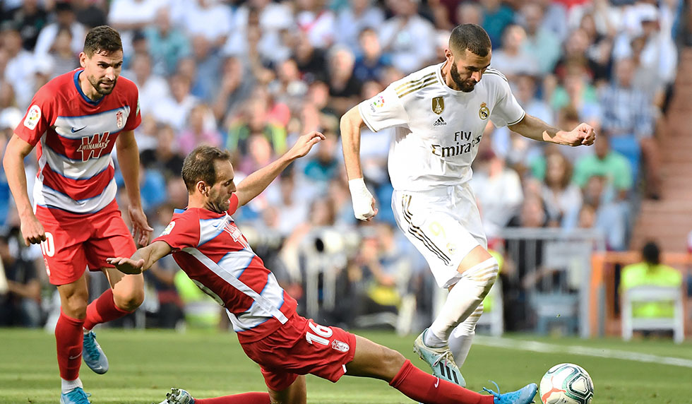 Granada's Spanish defender Victor Diaz (C) tackles Real Madrid's French forward Karim Benzema during the Spanish league football match between Real Madrid CF and Granada FC at the Santiago Bernabeu stadium in Madrid on October 5, 2019. (Photo by PIERRE-PHILIPPE MARCOU / AFP) (Photo by PIERRE-PHILIPPE MARCOU/AFP via Getty Images)
