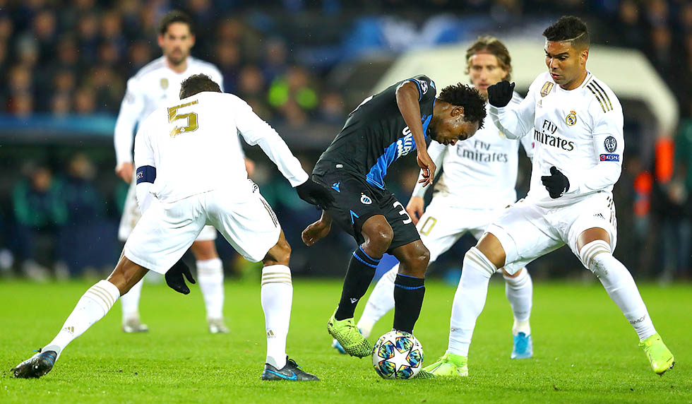 BRUGGE, BELGIUM - DECEMBER 11: Percy Tau of Club Brugge is challenged by Raphael Varane and Casemiro of Real Madrid during the UEFA Champions League group A match between Club Brugge KV and Real Madrid at Jan Breydel Stadium on December 11, 2019 in Brugge, Belgium. (Photo by Dean Mouhtaropoulos/Getty Images)