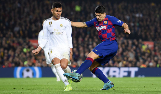 BARCELONA, SPAIN - DECEMBER 18: Luis Suarez of Barcelona takes a shot at goal under pressure from Casemiro of Real Madrid during the Liga match between FC Barcelona and Real Madrid CF at Camp Nou on December 18, 2019 in Barcelona, Spain. (Photo by Alex Caparros/Getty Images)