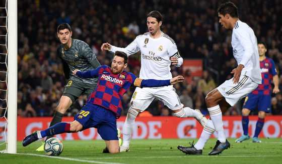 BARCELONA, SPAIN - DECEMBER 18: Lionel Messi of Barcelona stretches to keep the ball in play under pressure from Sergio Ramos of Real Madrid during the Liga match between FC Barcelona and Real Madrid CF at Camp Nou on December 18, 2019 in Barcelona, Spain. (Photo by Alex Caparros/Getty Images)