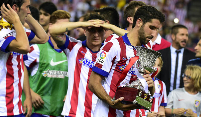 Atletico Madrid's midfielder Raul Garcia (R) holds the Super Cup trophy at the end of the Spanish Supercopa second-leg football match Atletico de Madrid vs Real Madrid CF at the Vicente Calderon Stadium in Madrid on August 22, 2014. Atletico de Madrid won 1-0. AFP PHOTO/ GERARD JULIEN (Photo credit should read GERARD JULIEN/AFP via Getty Images)
